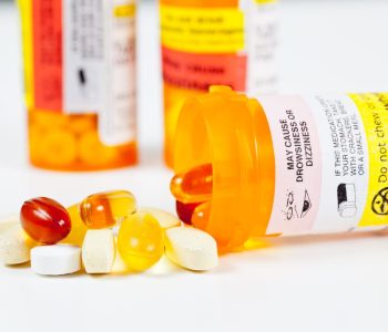 Colorful vitamins spilling from prescription bottle with warnings